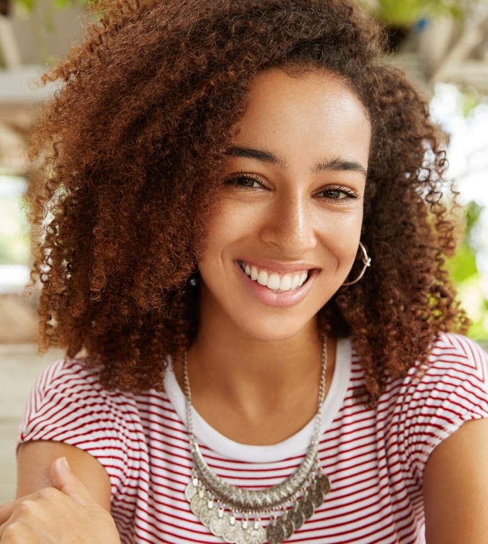Young woman with curly hair grinning after a smile makeover in Norman
