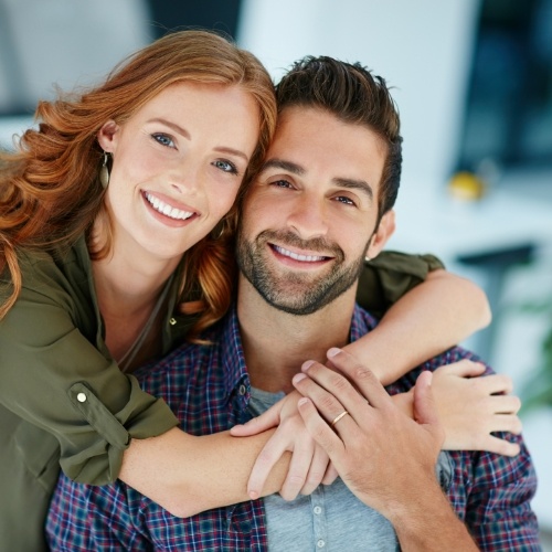 Man and woman hugging from the side after smile makeover