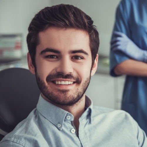 Young man with short beard smiling in dental chair