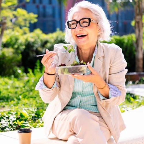 Lady smiles while eating salad