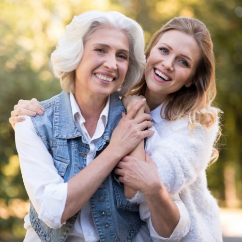 Mother and daughter holding each other and smiling outdoors