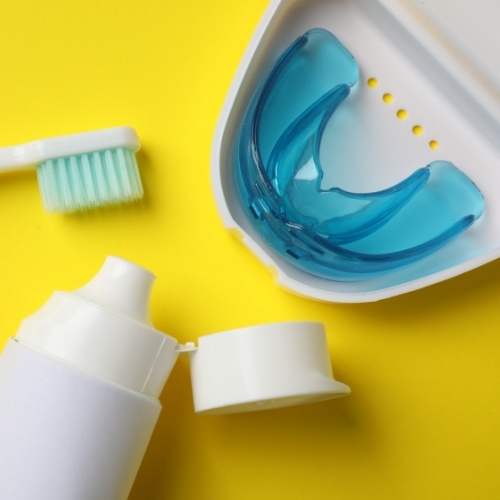 Blue mouthguard in carrying case next to a toothbrush and bottle of toothpaste