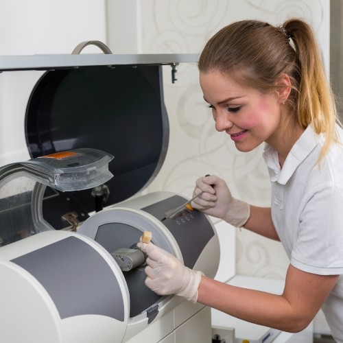 Dental team member placing a block of ceramic into CEREC machine