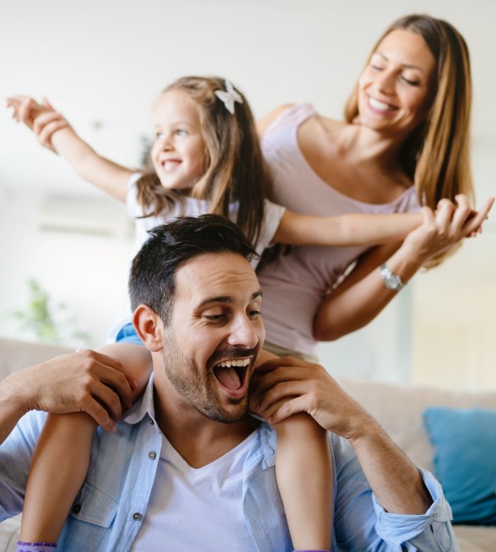 Mother and father playing with their young daughter after preventive dentistry in Norman