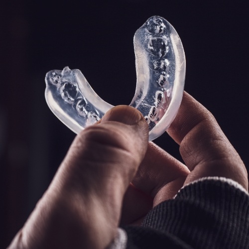 Person holding a clear athletic mouthguard in their hand