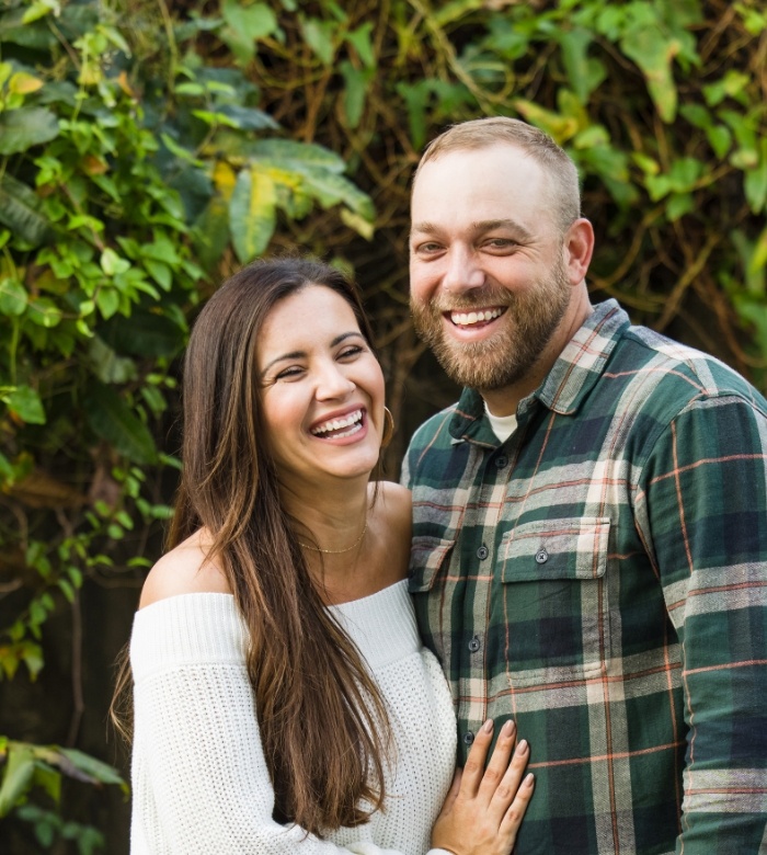 Laughing man and woman holding each other after cosmetic dental bonding in Norman