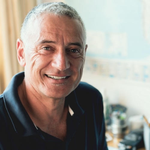 man in dark blue polo shirt smiling in kitchen