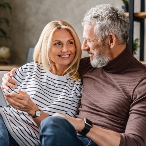 Older man and woman cuddling on couch