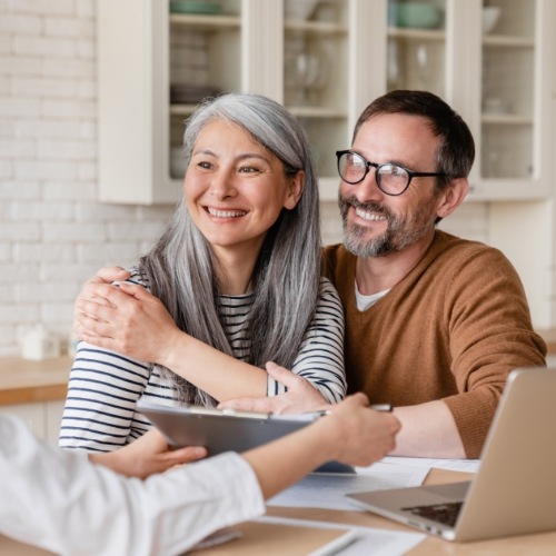 Man and woman sitting at kitchen table discussing dental implant cost