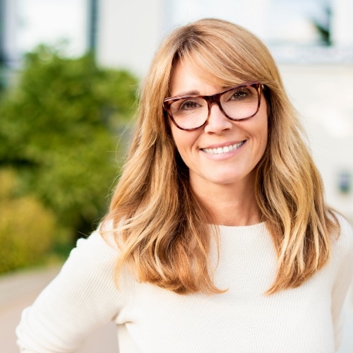 Blonde woman with glasses smiling outdoors