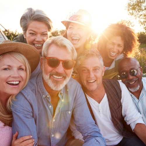 Group of older adults smiling together outdoors in late afternoon sun