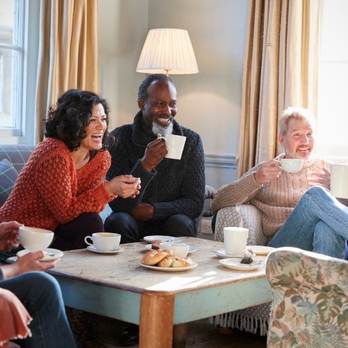 Group of older adults drinking coffee and watching T V