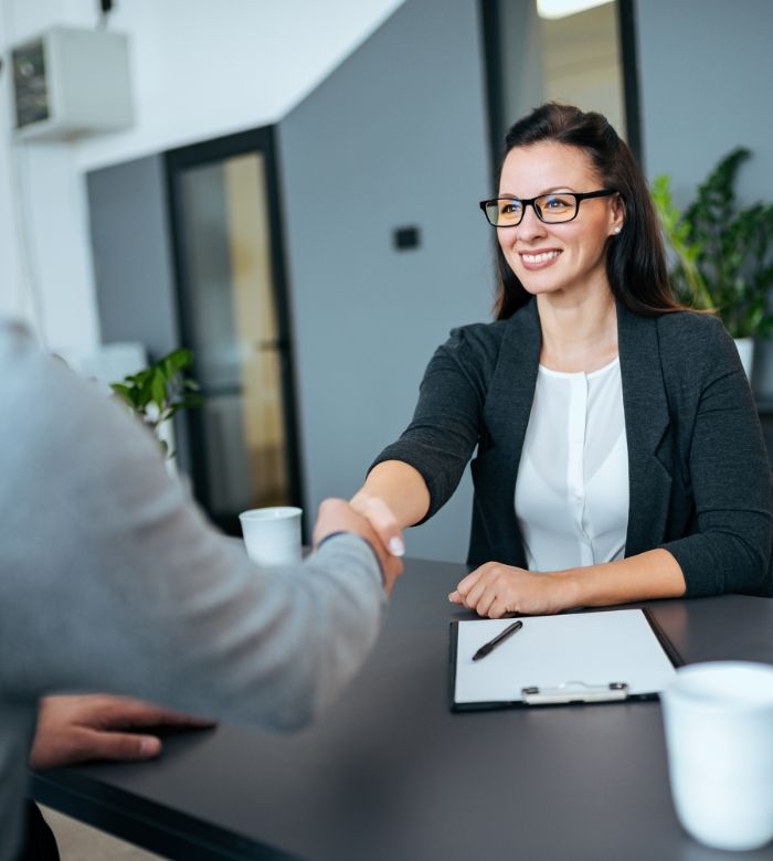 Woman shaking hands with dental team member while discussing dental insurance in Norman