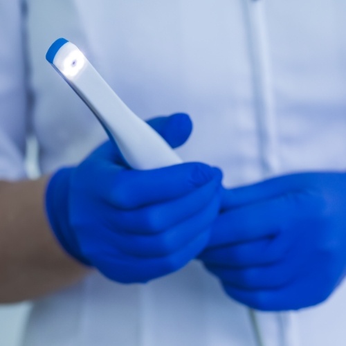 Dentist holding a thin white intraoral camera