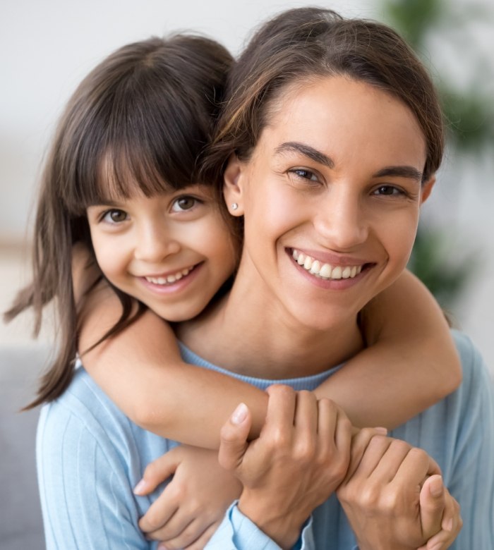 Young girl hugging her mother around the shoulders