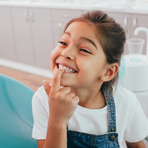 Little girl pointing to her smile while visiting children's dentist in Norman