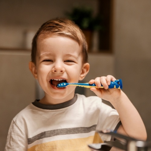 Young boy brushing his teeth with blue and yellow toothbrush