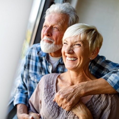 Older man and woman looking out a window together