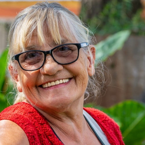 Senior woman in red blouse grinning outdoors