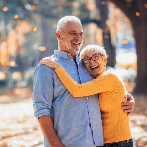 Older man and woman hugging at a park