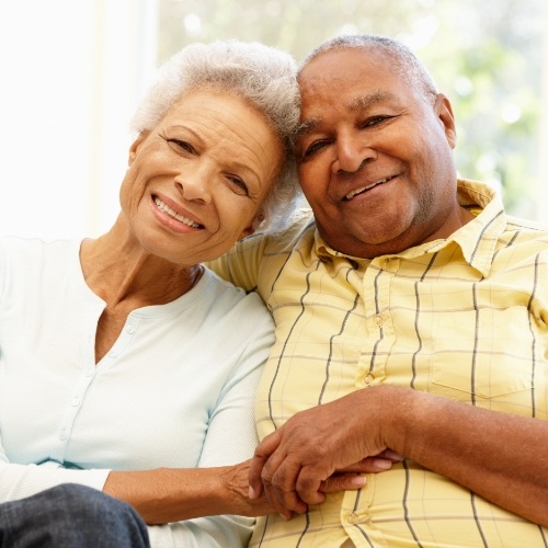 Older man and woman sitting next to each other and holding hands