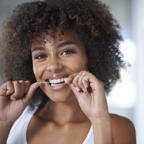 Woman smiling while flossing her teeth