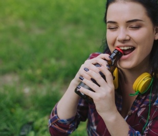 Woman opening a glass bottle with her teeth