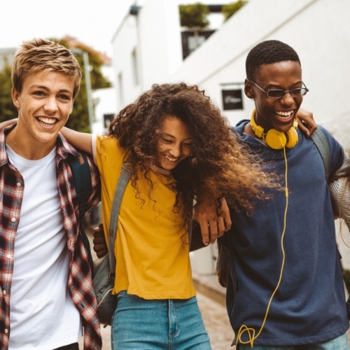 Three teenagers laughing together with white building in background