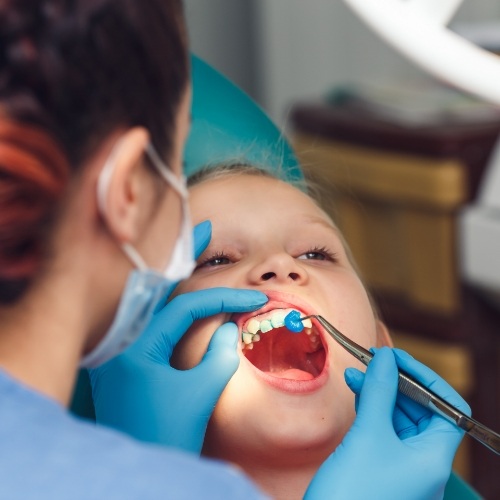 Young girl receiving fluoride treatment in dental office