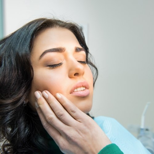 Woman touching her cheek while sitting in dental chair