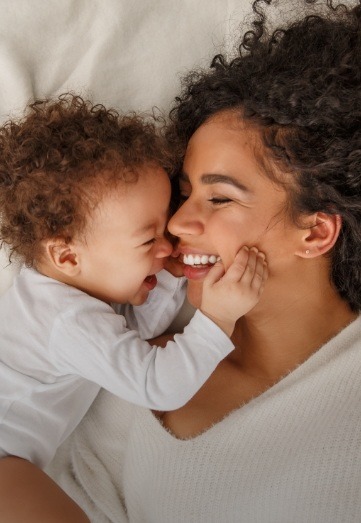 Smiling mother cuddling with her baby on a bed