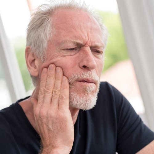 Older man holding the side of his face in pain