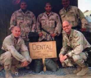 Group of man in army uniforms posing with a wooden sign that says dental