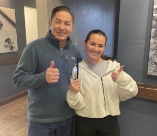 Doctor Carmen giving a thumbs up with a young woman in his dental office