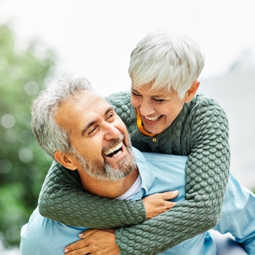 Older man and woman laughing outdoors