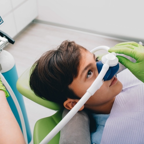 Young boy wearing nitrous oxide sedation mask in dental chair