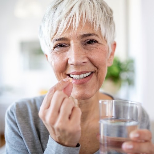 Woman holding pill and glass of water