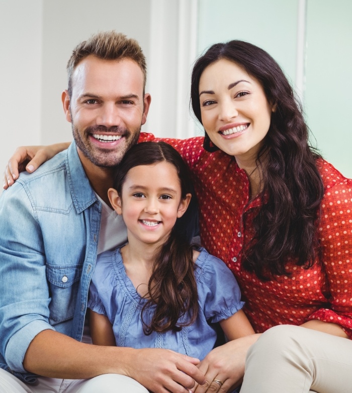 Mother father and young child smiling after receiving dental services in Norman