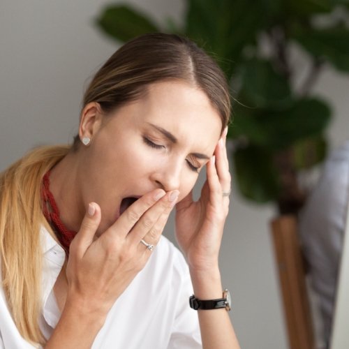 Woman with blonde ponytail yawning