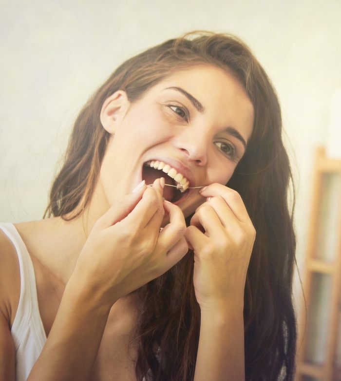 Woman smiling while flossing her teeth