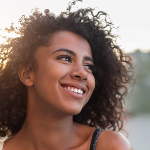 Young woman with curly hair smiling outdoors