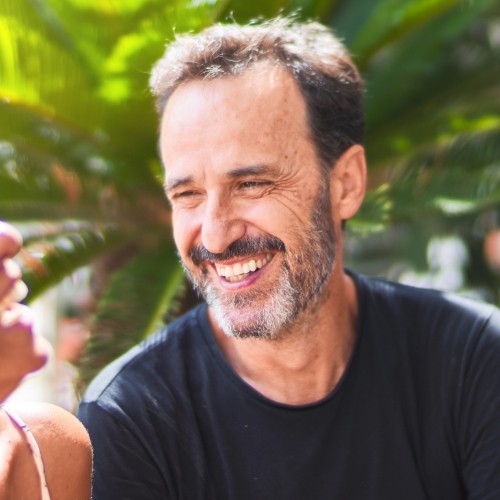 Bearded man in navy blue shirt grinning outdoors