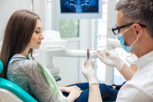 Dentist showing patient a dental implant model