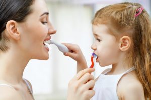 A mother and daughter brushing their teeth.