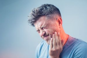 man with dental emergency holding mouth in pain 