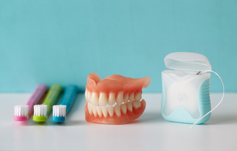 Dentures next to toothbrushes and floss