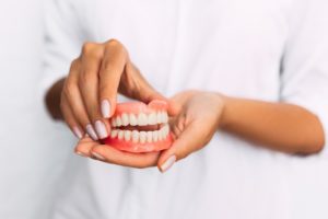 Hands holding new set of dentures.