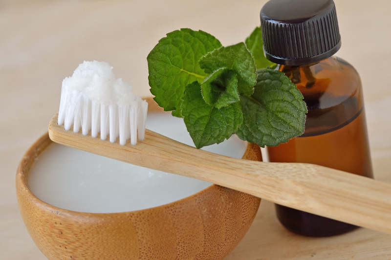 Table with DIY teeth whitening items like coconut and baking soda on toothbrush 