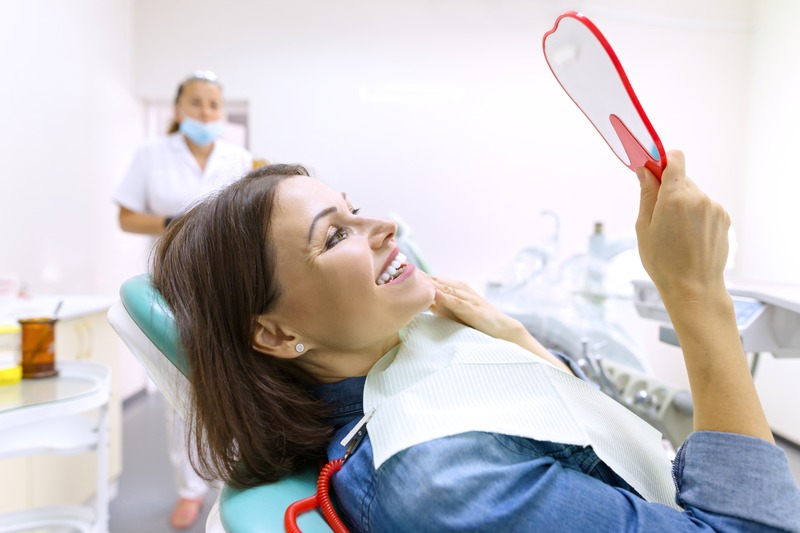 Patient smiling in mirror after getting dental fillings